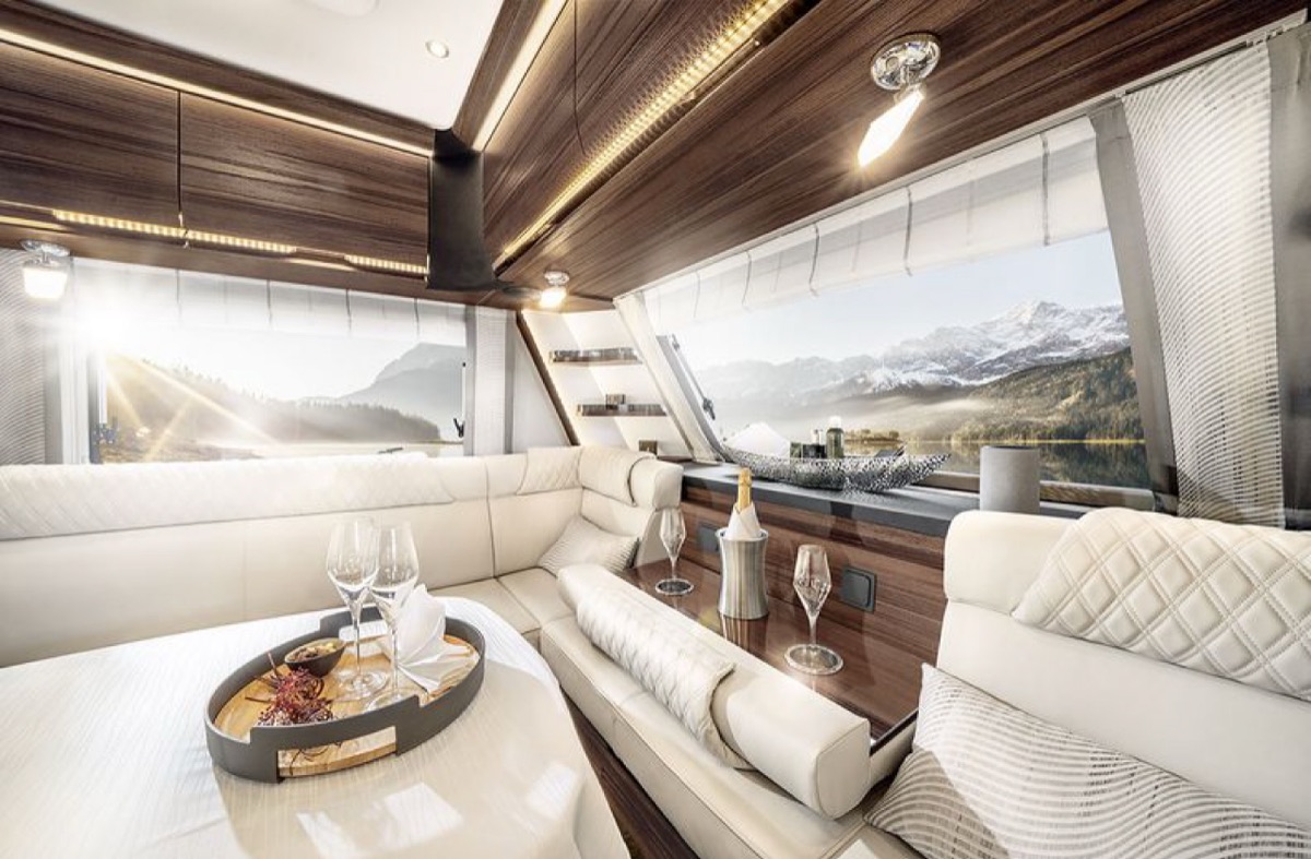 Caravan-Innenraum mit Sitzgruppe, gedecktem Tisch und warmer Holzoptik